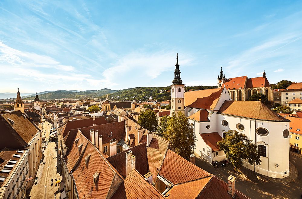 Panoramablick auf die Altstadt von Krems mit Kirchen und roten Dächern.
