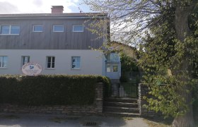 Zweistöckiges Gebäude mit Schild 'Alpengasthaus Ewin' und Garten.