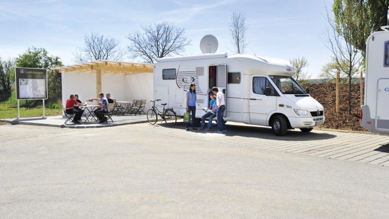 Reisemobilstellplatz Langenlois, © POV, Robert Herbst Reisemobilstellplatz mit Wohnmobil und Personen, die sich unterhalten.