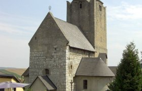 Historische Wehrkirche mit steinernem Turm und Spitzdach.