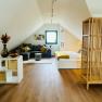 Gem&uuml;tliches Dachgeschoss-Apartment mit Sofa, Bett und Holzboden.