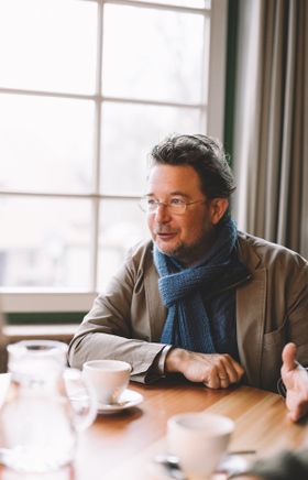 In einem gemütlichen Café, umgeben von der malerischen Natur des Waldviertels, genießt ein Mann in einem eleganten Outfit eine Tasse Kaffee. Die sanften Farben und das warme Licht schaffen eine einladende Atmosphäre, die zum Verweilen und Entspannen einlädt.