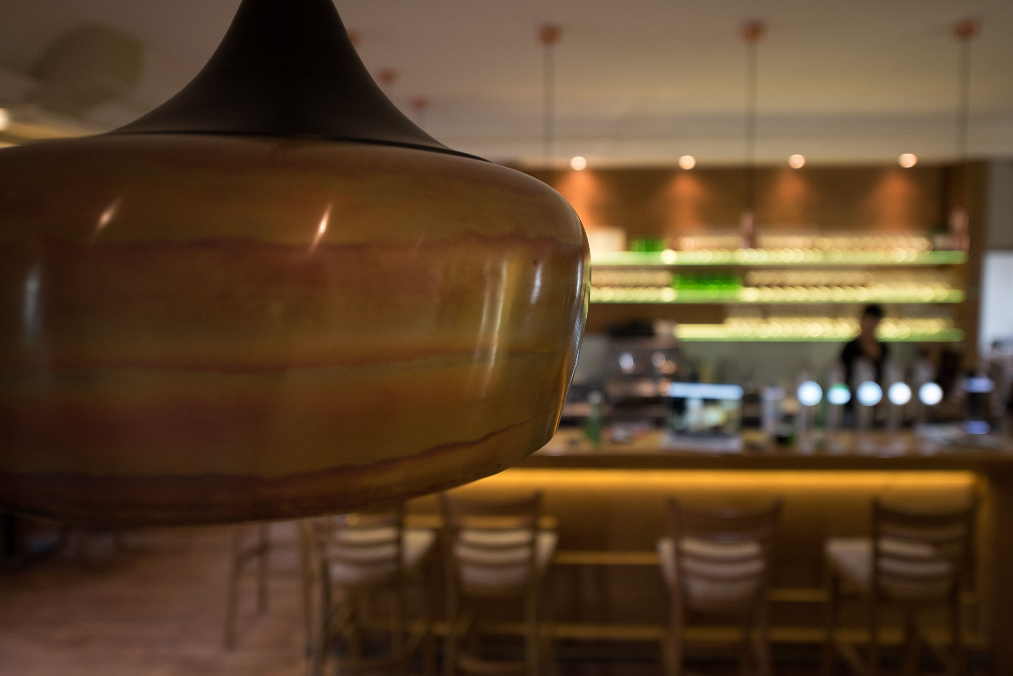 Nahaufnahme einer Lampe in einem stilvollen Café mit Bar im Hintergrund.