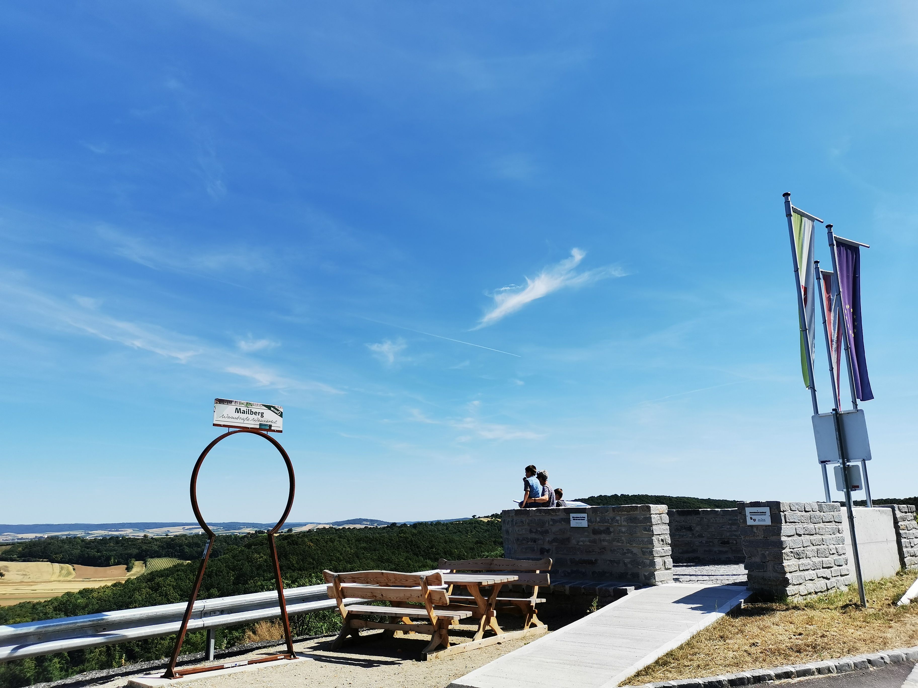 Aussichtspunkt mit Bänken und Fahnen, Blick auf Landschaft.