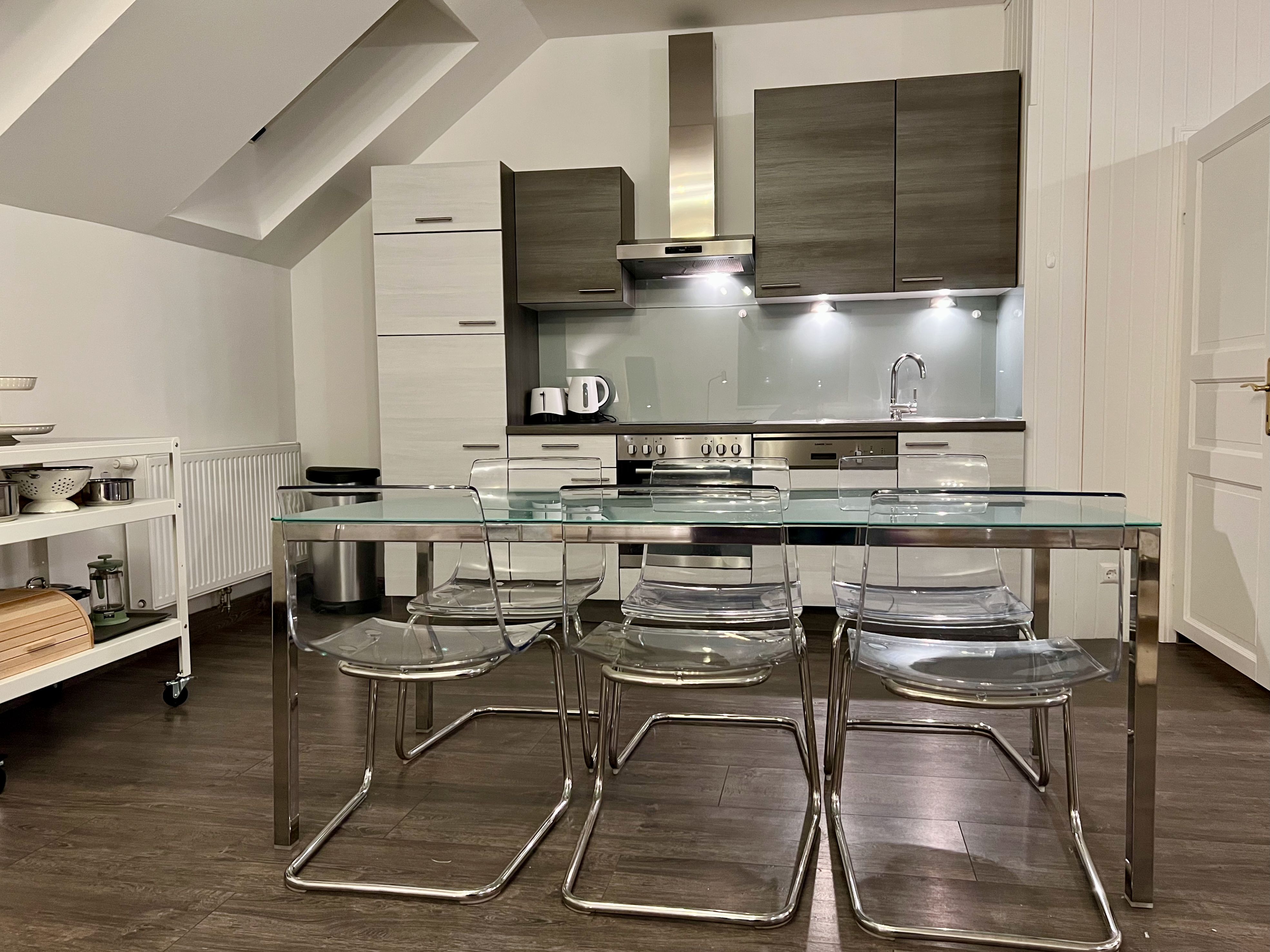 Moderne Küche mit Glas-Esstisch und transparenten Stühlen in einem Loft.