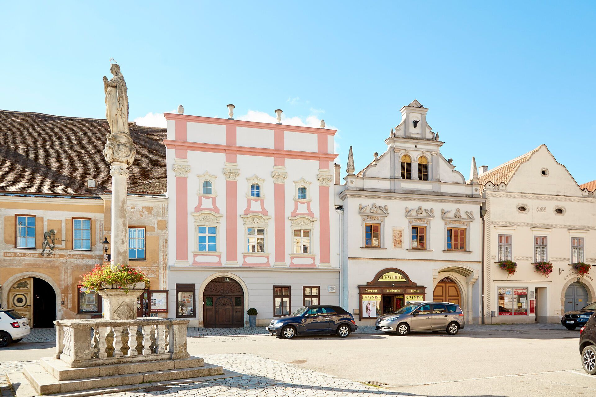 Historische Gebäude am Hauptplatz von Eggenburg mit einer Statue im Vordergrund.