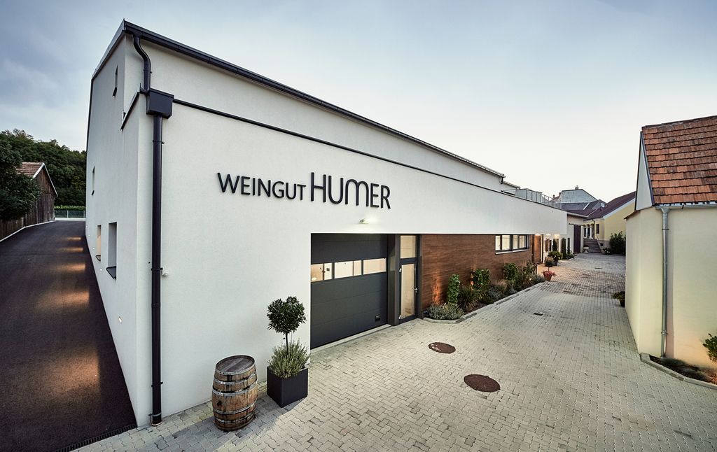 Modernes Gebäude des Weinguts Humer mit gepflastertem Hof und Pflanzen.