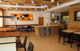 Innenansicht eines modernen Restaurants mit Holzelementen und Weltkarten-Dekor.