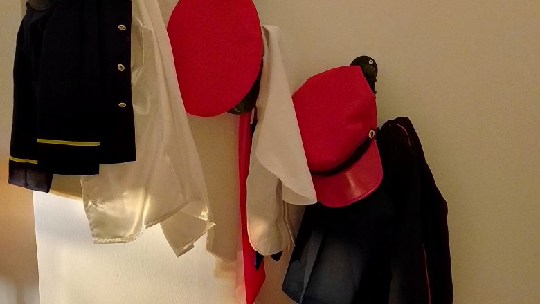 Uniformteile und Mützen an einer Wand aufgehängt.