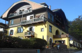 Ein traditionelles Hotel mit gelber Fassade und Holzbalkonen, dekoriert mit Blumen.