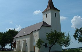 Filialkirche Pöllaberg mit Turm und Bäumen im Vordergrund.