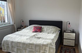 Ein Schlafzimmer mit einem Doppelbett, zwei Nachttischen und Teppichen auf Holzboden.