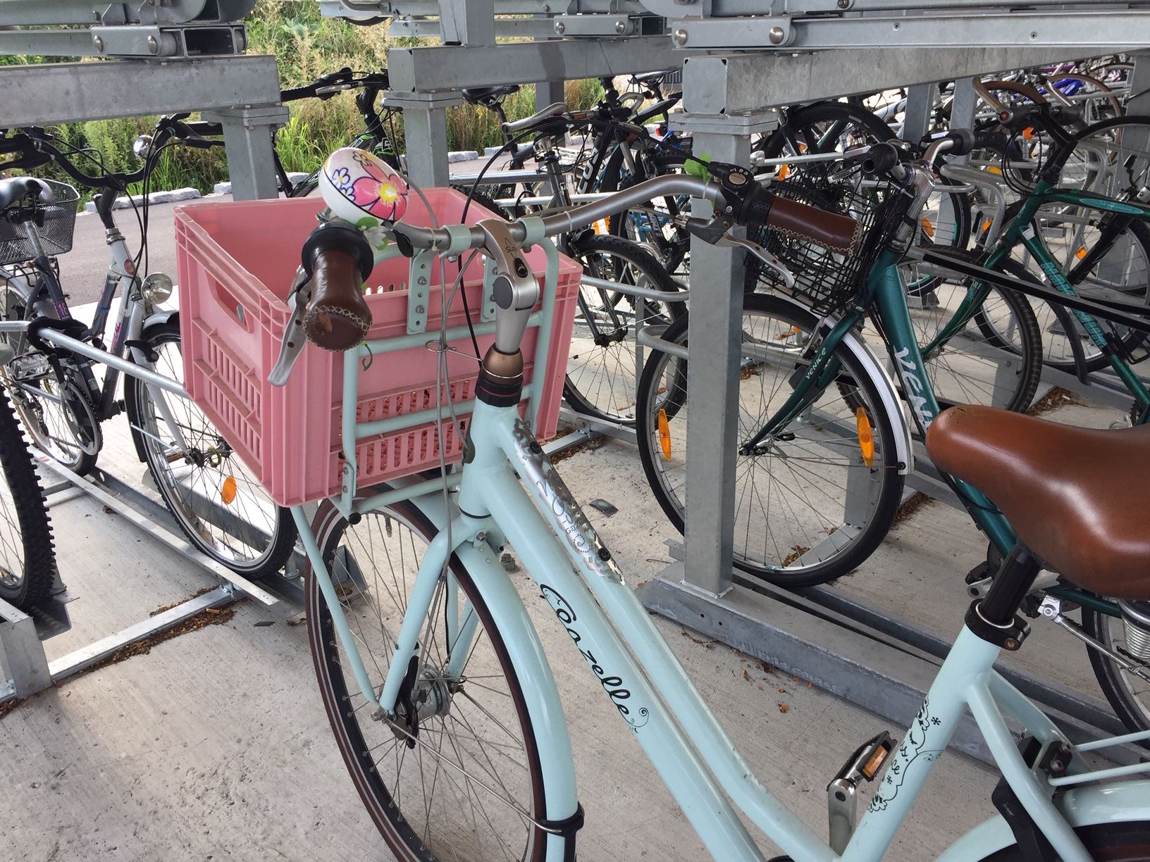 Fahrrad mit rosa Kiste in einem Fahrradständer.