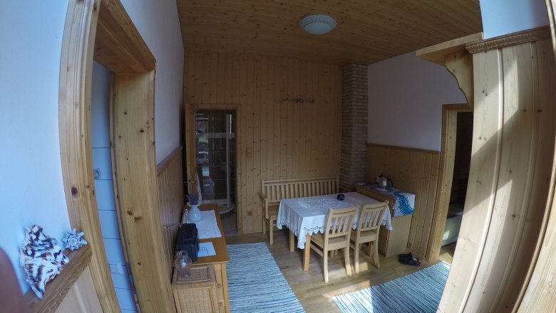 Esszimmer mit Holzw&auml;nden, Tisch und St&uuml;hlen, Teppichen und Dekorationen.