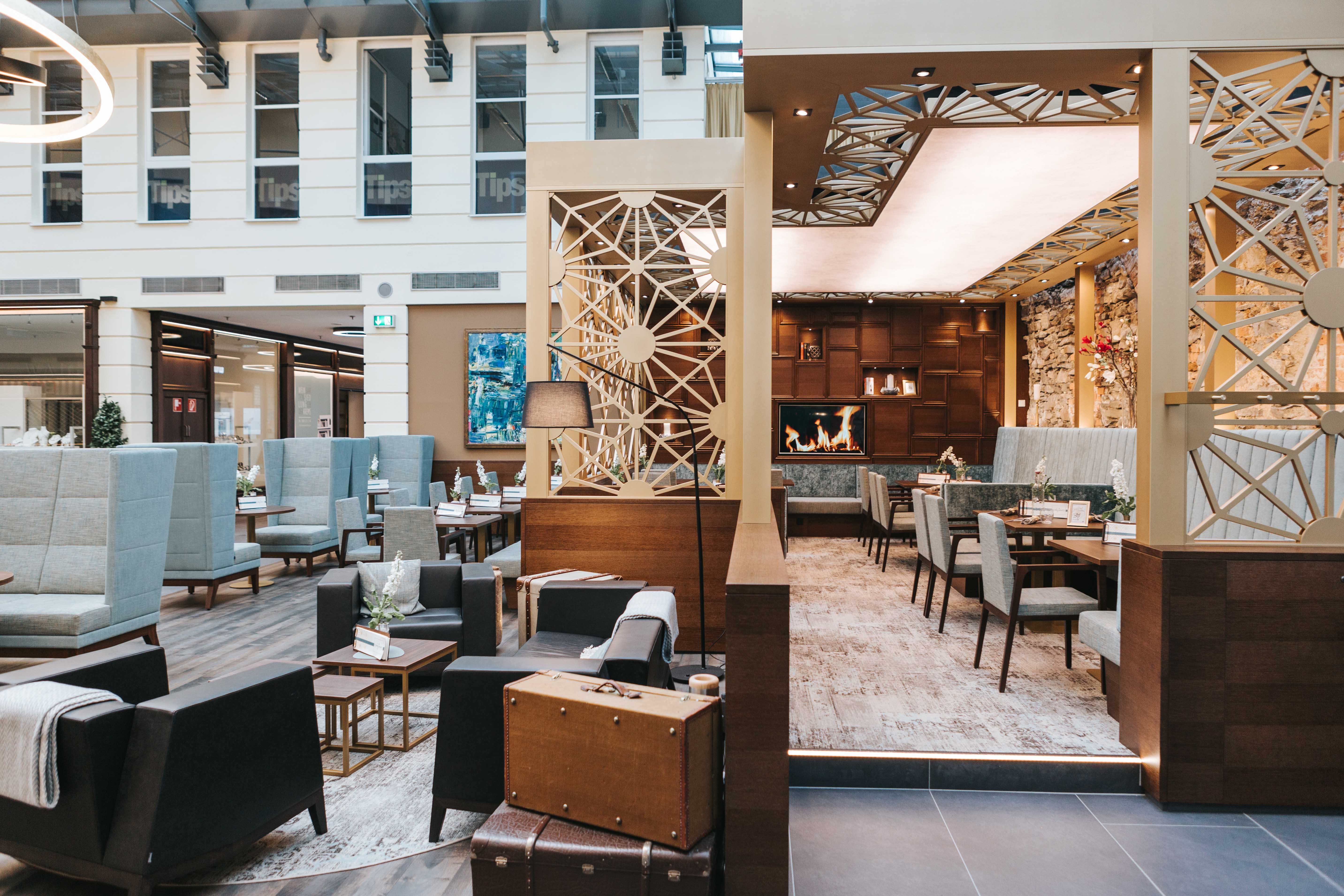 Innenansicht eines modernen Cafés mit gemütlichen Sitzbereichen, Kamin und stilvoller Dekoration.