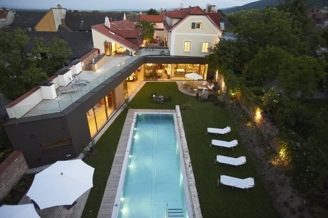 Luftaufnahme eines modernen Hauses mit Pool und Garten bei Abendd&auml;mmerung.