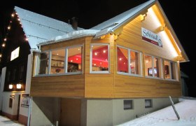 Ein beleuchtetes Gebäude im Schnee mit dem Schild 'Schistadl'.