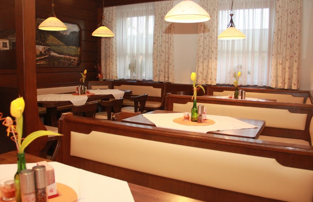 Gemütliches Stüberl mit Holzmöbeln, Tischdekoration und Lampen.