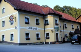 Ein traditionelles Gasthaus mit gelber Fassade und roten Dachziegeln.