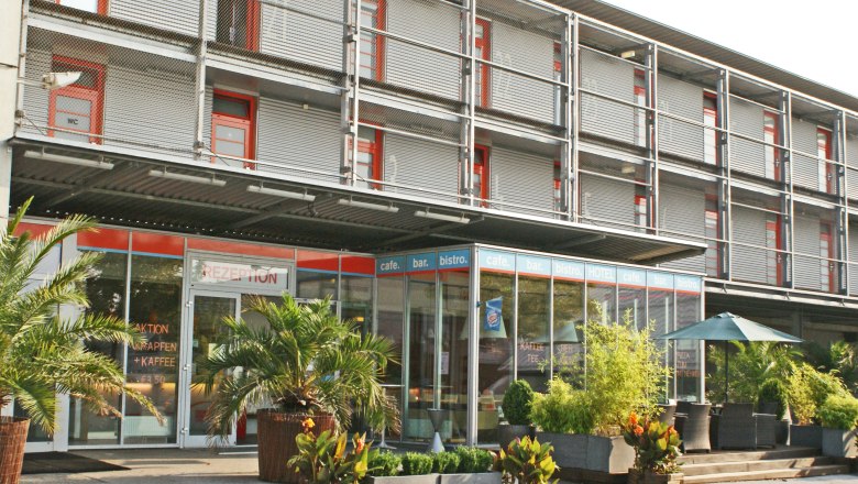 Moderne Hotel-Fassade mit Glasfront und Pflanzen.