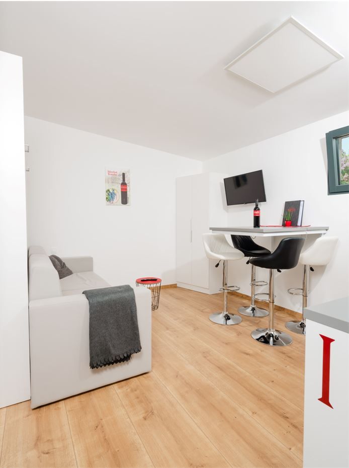 Modernes Wohnzimmer mit Sofa, Esstisch und Barhockern.