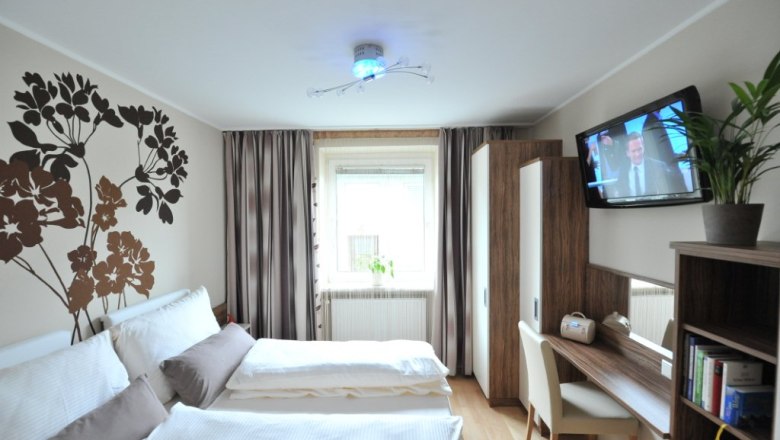 Ferienwohnung Datler, © Ferienwohnung Datler Ein modernes Schlafzimmer mit Doppelbett, Wanddekoration, Schreibtisch, Fernseher und Pflanzen.