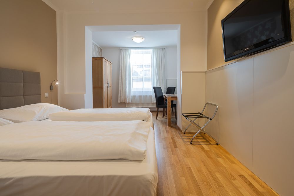 Hotelzimmer mit zwei Betten, Fernseher, Tisch und Stühlen.