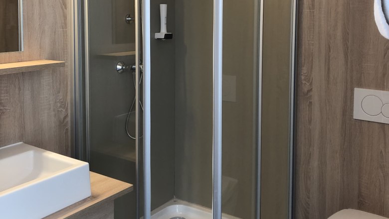 Modernes Badezimmer mit Dusche, Waschbecken und Toilette.