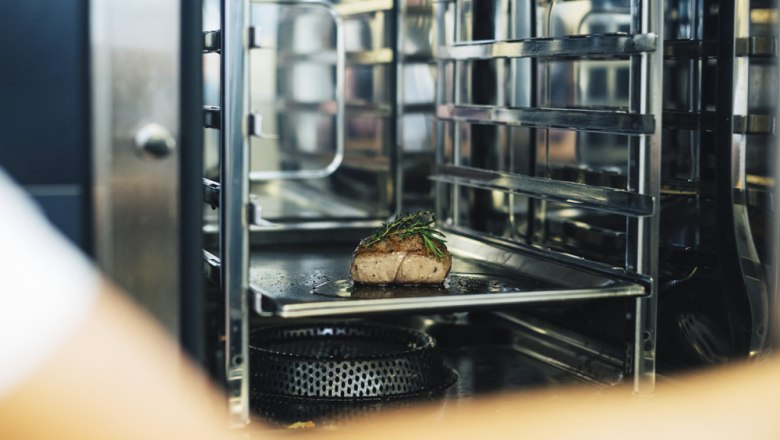 Ein St&uuml;ck Fleisch mit Kr&auml;utern in einem professionellen Ofen.