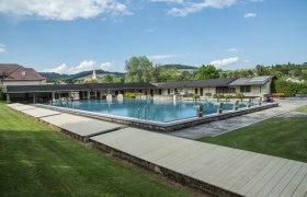 Freibad Krumbach mit Schwimmbecken und Sprungbl&ouml;cken, umgeben von gr&uuml;ner Landschaft und Geb&auml;uden.