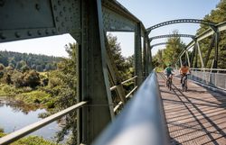 Die sanfte Brise weht über die Thayabrücke, während Radfahrer die malerische Landschaft genießen. Umgeben von üppigem Grün und dem sanften Plätschern des Wassers, lädt dieser Ort dazu ein, die Schönheit der Natur zu erleben und die Seele baumeln zu lassen.