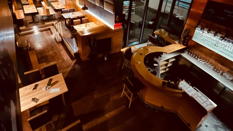 Innenansicht Brauhaus Schwechat bei Nacht mit Holztischen und einer Bar.