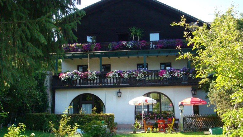 Ein traditionelles Gasthaus mit Holzbalkon und Blumen in Scheibbs, umgeben von einem grünen Garten.
