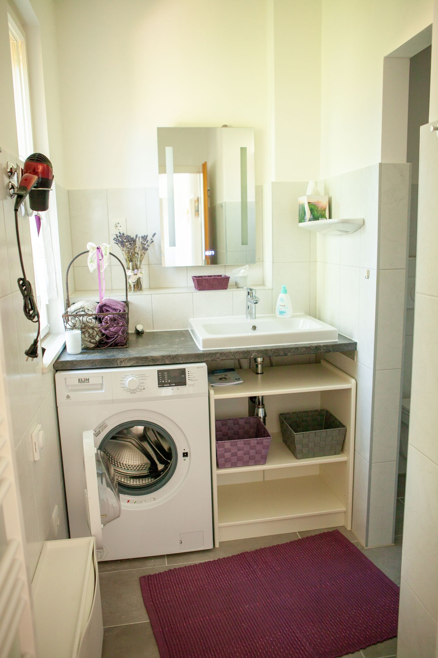 Modernes Badezimmer mit Waschmaschine, Waschbecken und Spiegel.