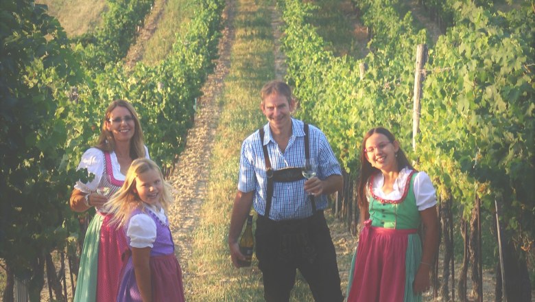 Familie in traditioneller Kleidung in einem Weinberg.