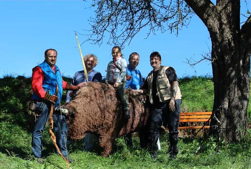 Gruppe von Menschen posiert mit einem Bogenschießziel in Form eines Bären im Freien.