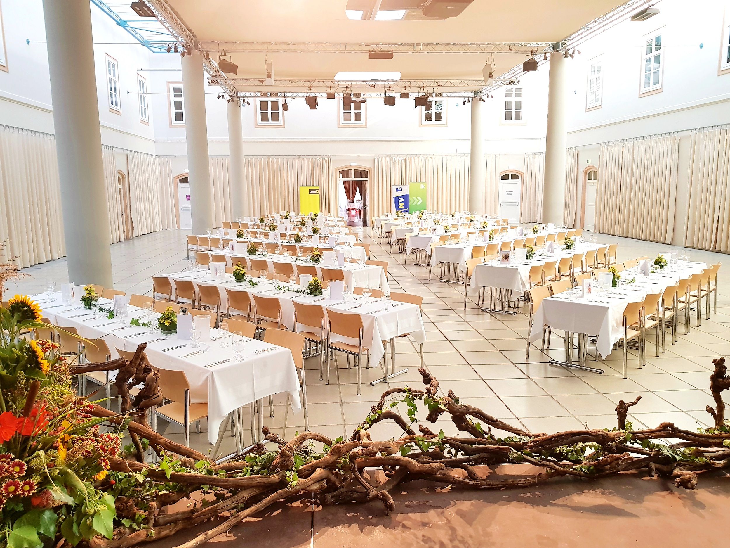 Ein festlich dekorierter Saal mit gedeckten Tischen und Blumenschmuck im Atrium Tulln.