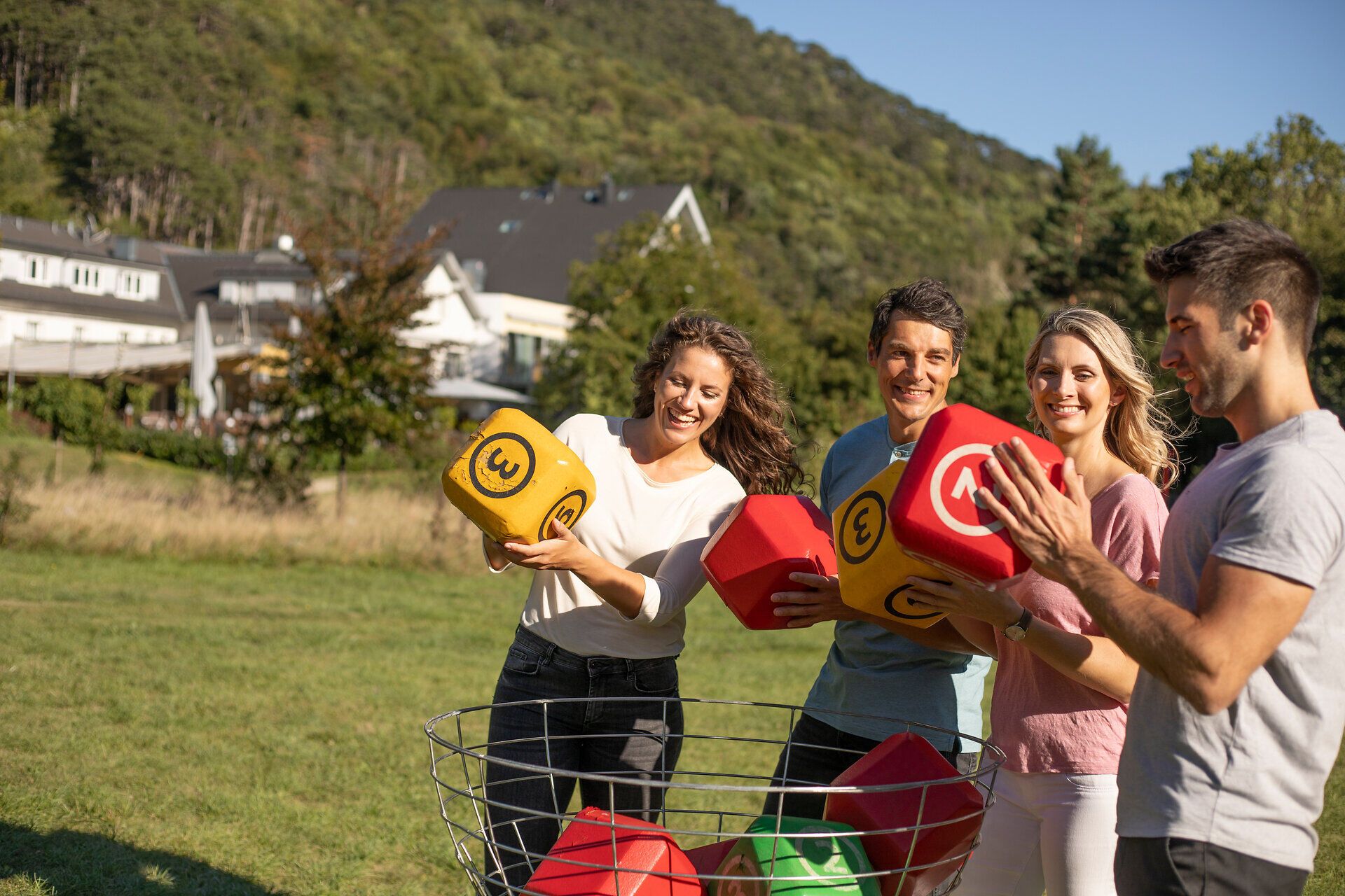 Inmitten der grünen Wiesen und sanften Hügel des Spirit Parks genießen fröhliche Menschen ein Spiel mit bunten Würfeln. Die Sonne strahlt vom blauen Himmel und schafft eine einladende Atmosphäre für Spaß und Geselligkeit.