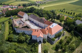 Luftaufnahme von Schloss Mailberg mit umliegender Landschaft.