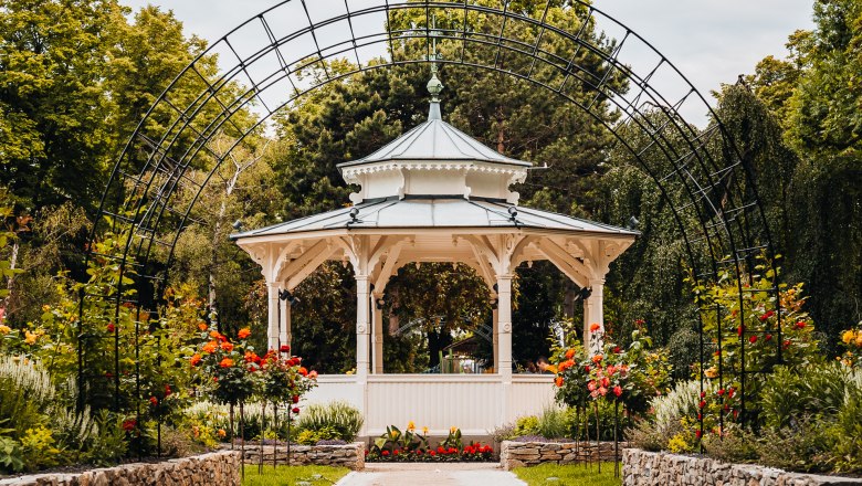 Wei&szlig;er Pavillon hinter Rosenbogen