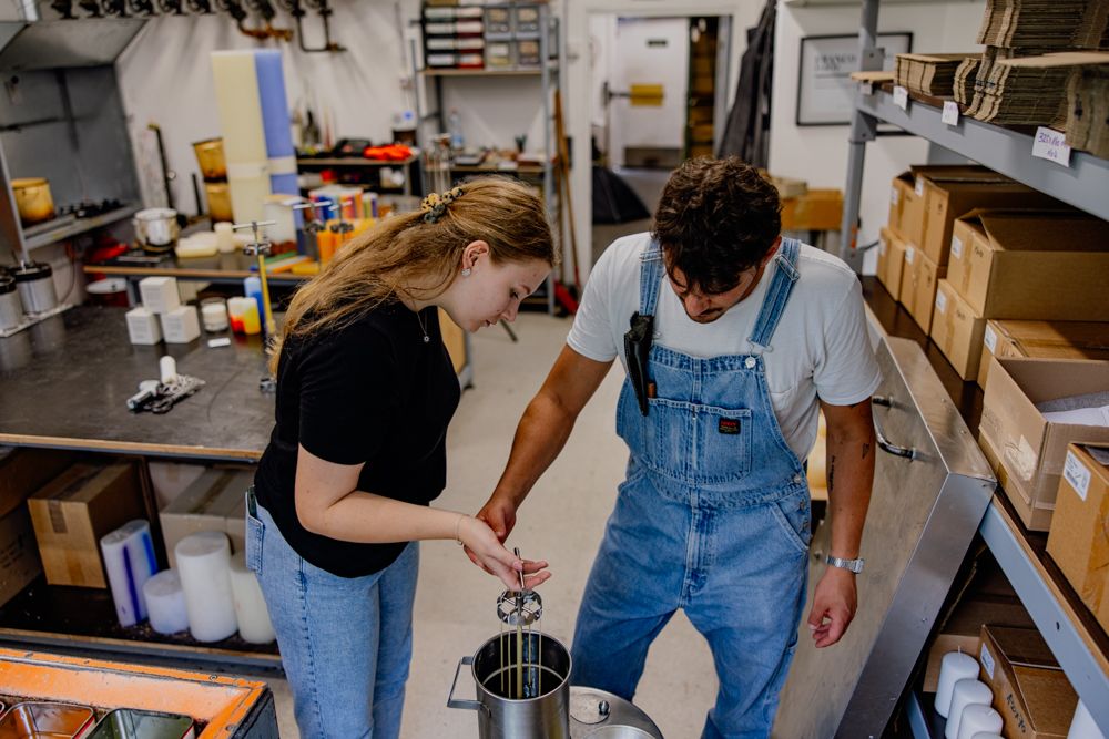 Zwei Personen ziehen Kerzen in einer Werkstatt.