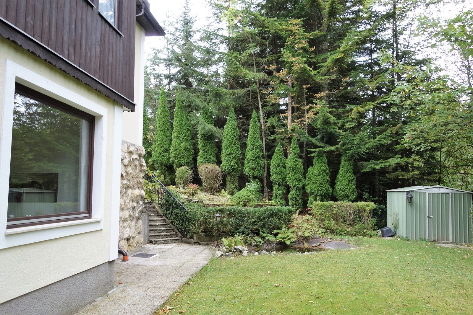 Garten mit Rasen, Bäumen und einem Schuppen.