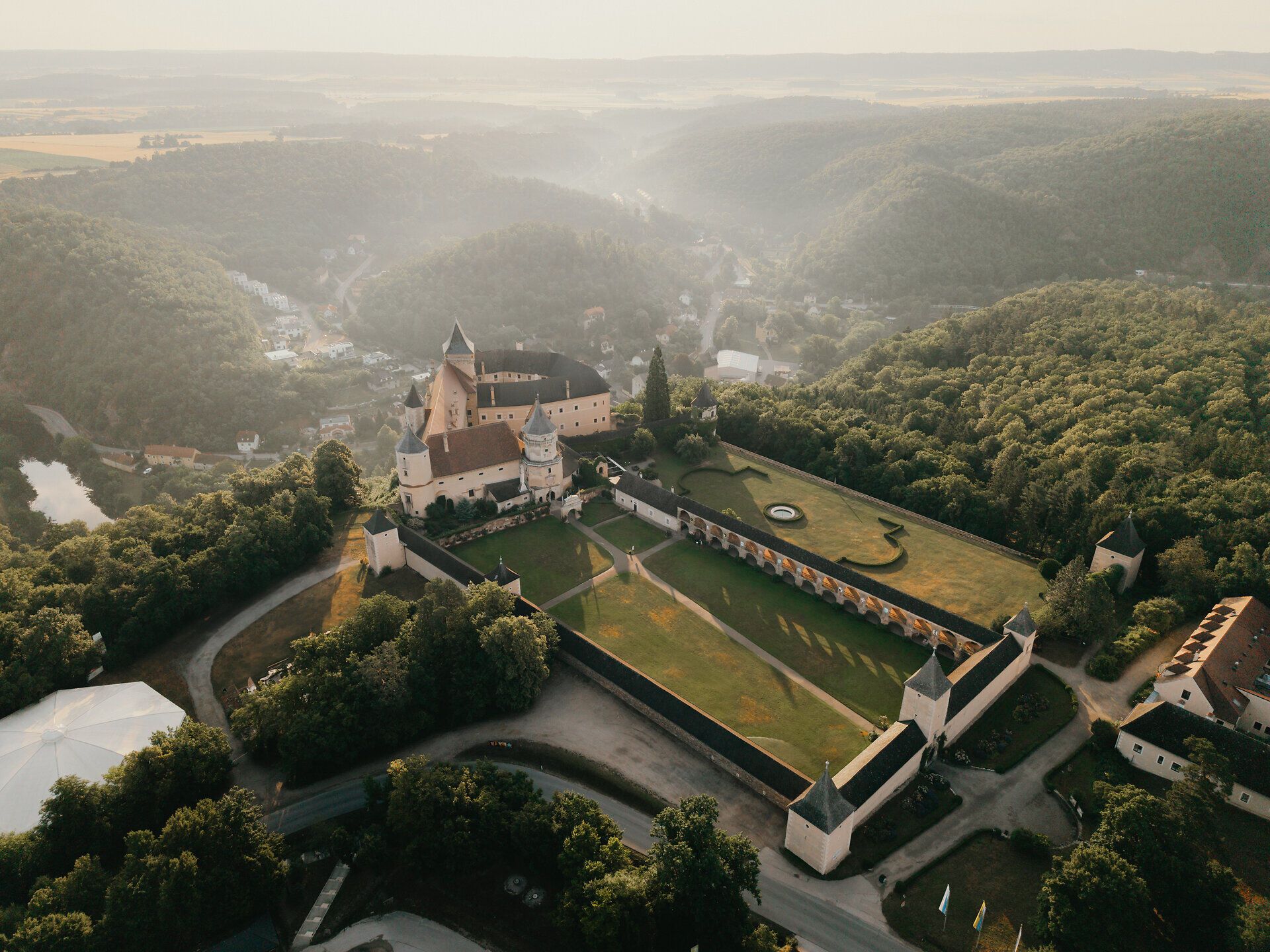 Luftaufnahme von Schloss Rosenburg inmitten bewaldeter Hügel im Waldviertel.