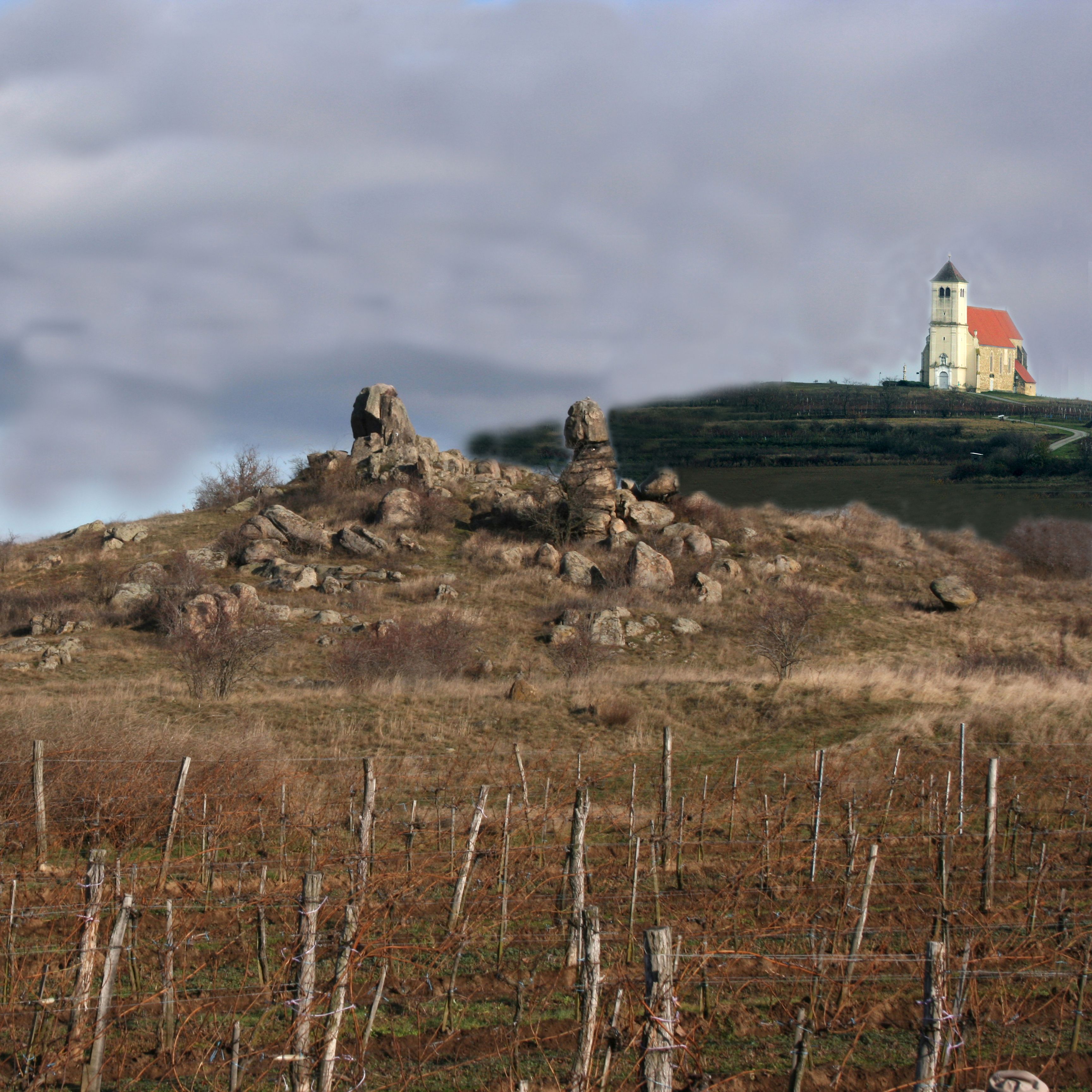 Landschaft mit Felsenformationen und Kirche im Hintergrund.