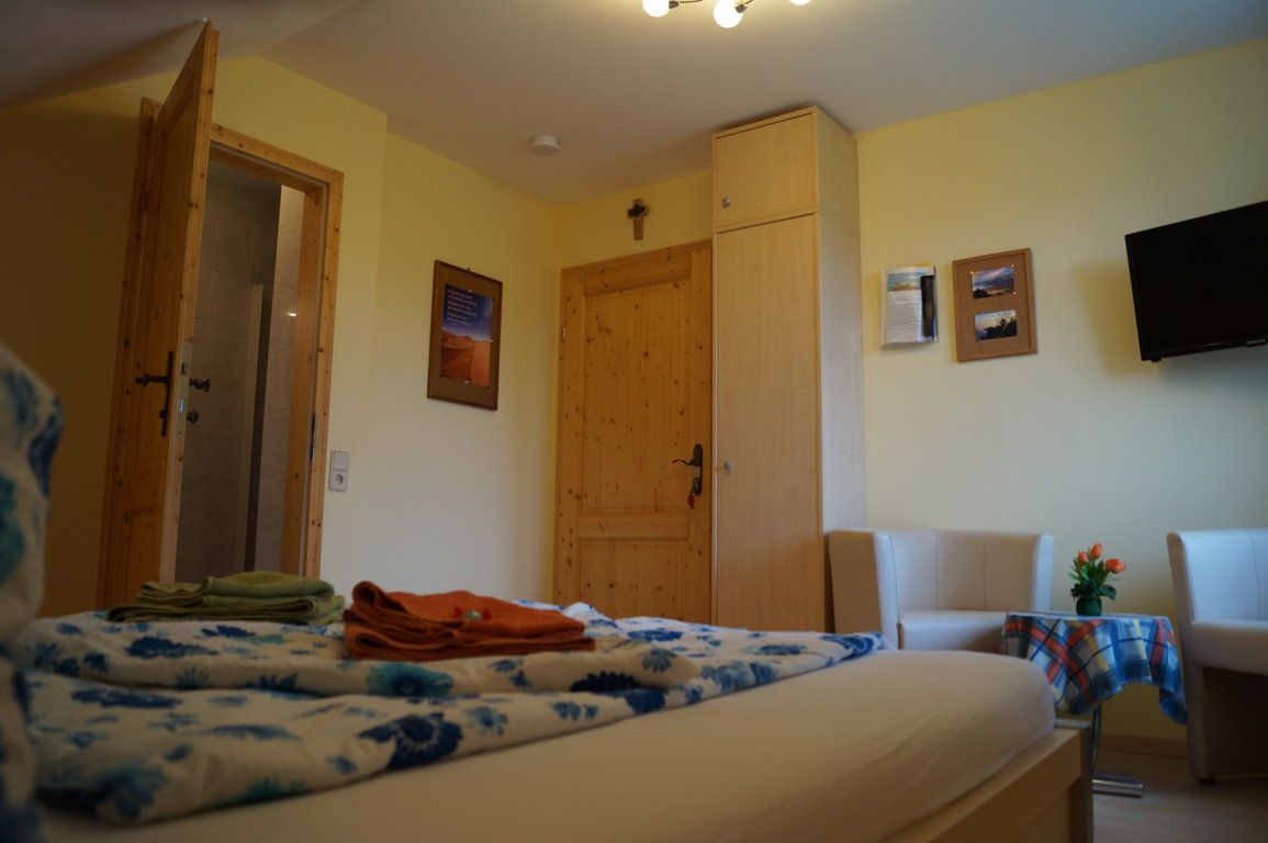 Gemütliches Hotelzimmer mit Holzmöbeln, Bett, Fernseher und Sitzbereich.