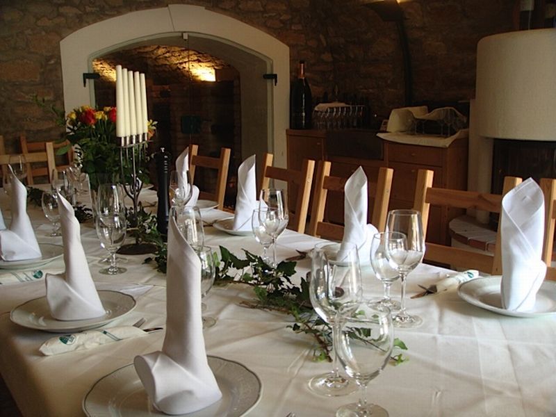 Elegante Tafel mit weißen Servietten und Weingläsern in einem rustikalen Raum.