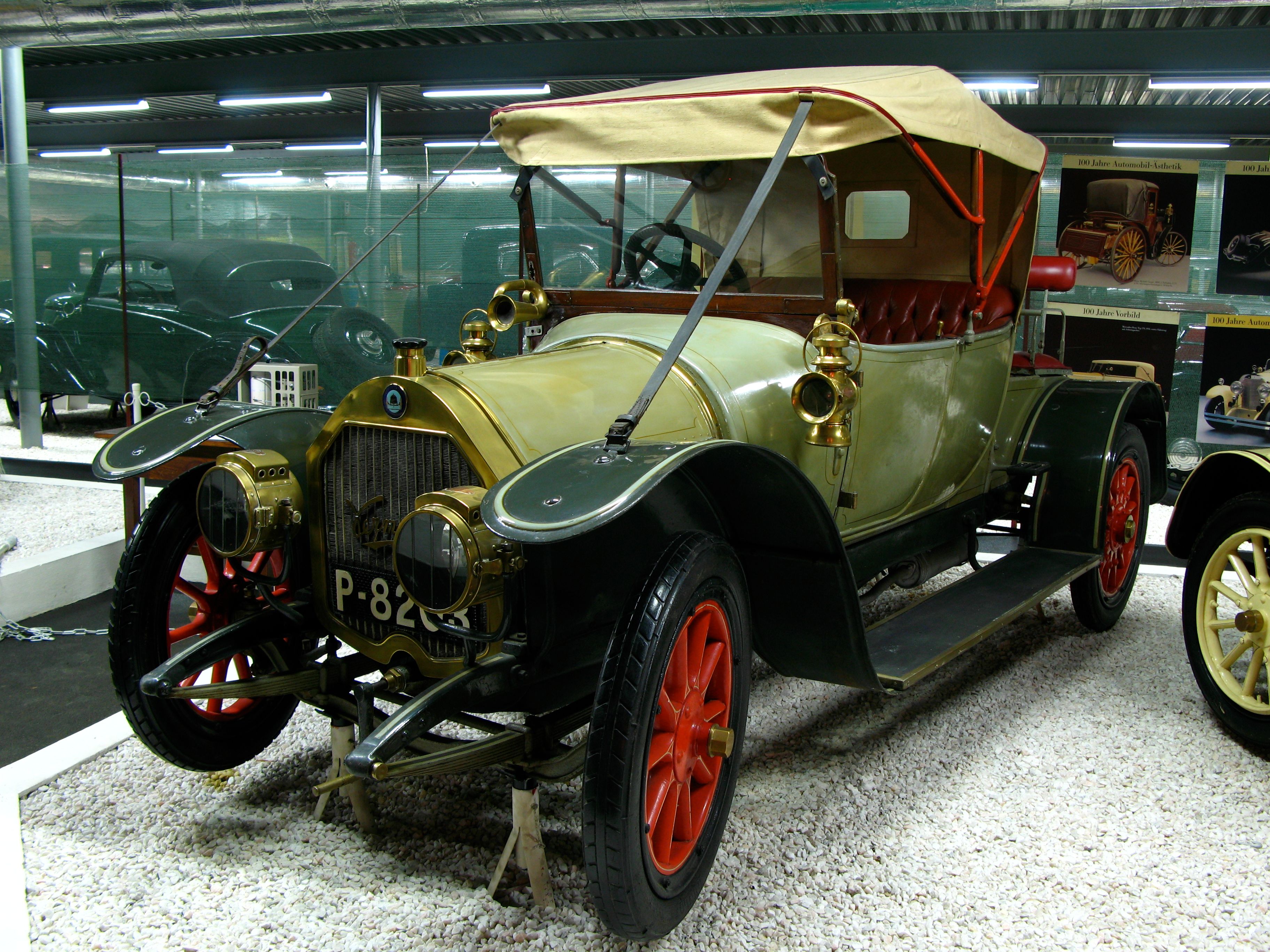Ein Oldtimer mit rotem Verdeck und roten Rädern in einem Automobilmuseum.