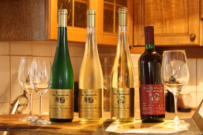 Vier Weinflaschen und Gläser auf einem Tisch in einer Küche.