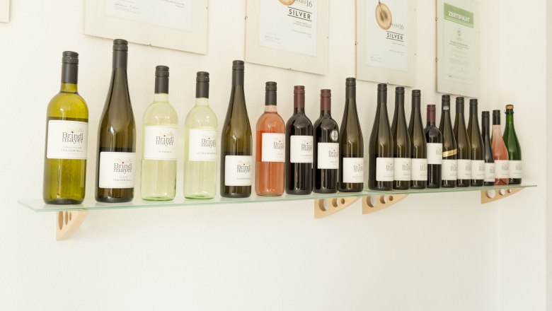 Regal mit Brindlmayer Weinflaschen und Auszeichnungen an der Wand.