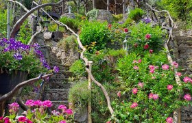 Steintreppe mit Blumen und Holzgel&auml;nder in einem Garten.